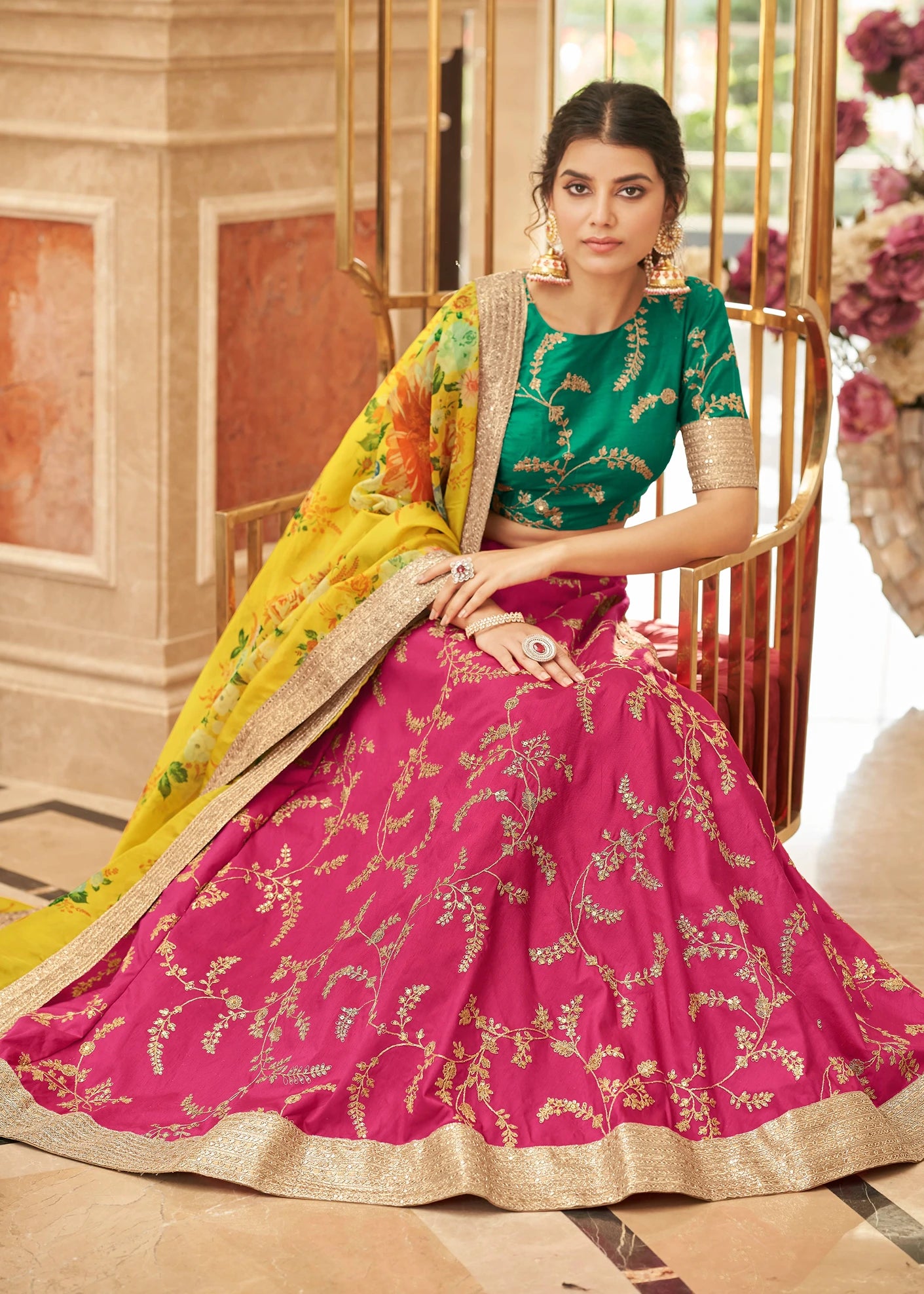 Bride in rani pink circular lehenga with triple layer can-can, wearing contrast green raw silk blouse with gold piping, yellow floral organza dupatta mid-twirl, resham embroidery on lehenga panels, lightweight colorblock lehenga in Mauritius for sangeet and carnival wedding functions.