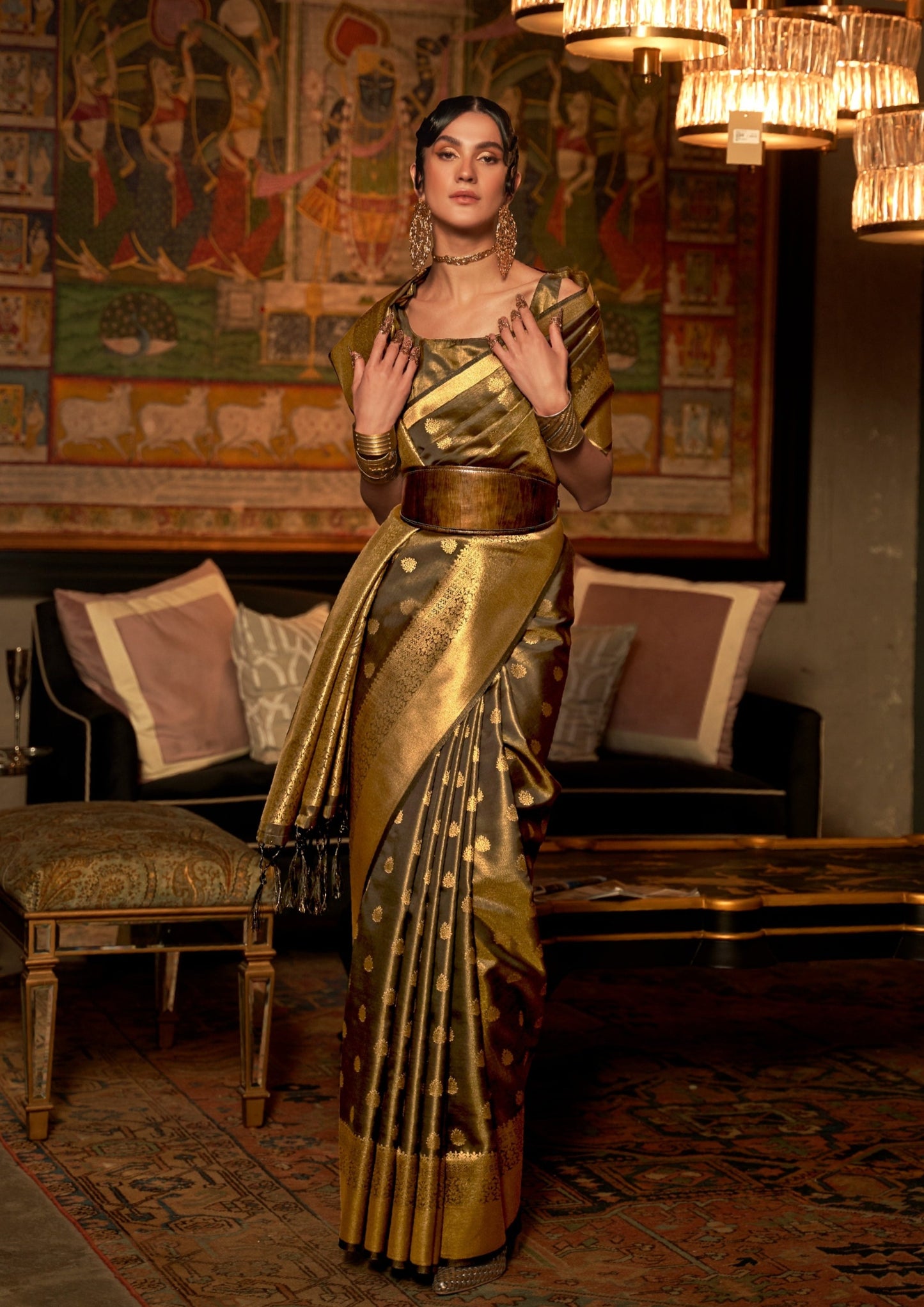 woman in black saree with golden border standing in front of black sofa on a carpet