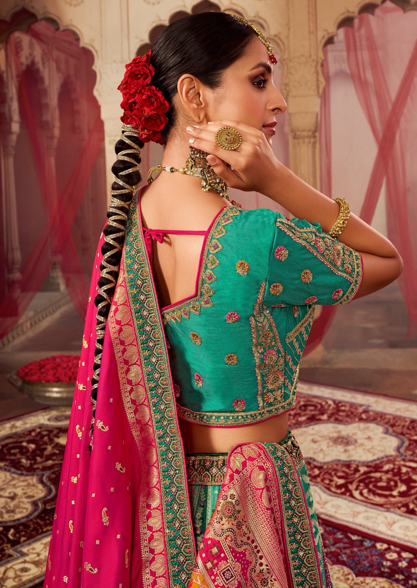 Bride back pose in green lehenga choli with pink dupatta.