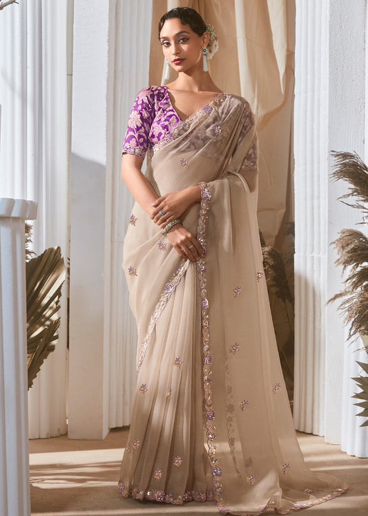 Beige organza tissue silk embroidered saree with purple printed blouse.