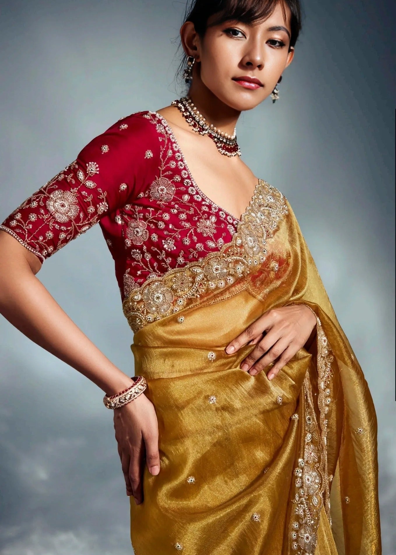 Golden yellow color bridal tissue silk saree with embroidery work ideal for festive wear having red blouse piece.