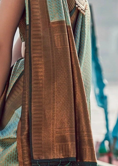 Close-up of pure kanjivaram silk saree in pastel green pista color featuring heavy copper zari weaving on black pallu.