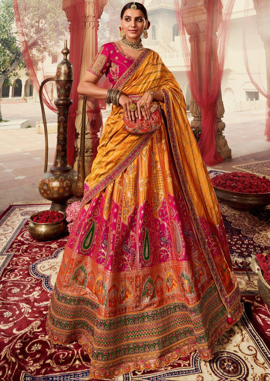 A woman wearing a traditional Indian bridal lehenga choli in pink and yellow color combination with stone work and floral patterns, paired with a dupatta with heavy work on borders.