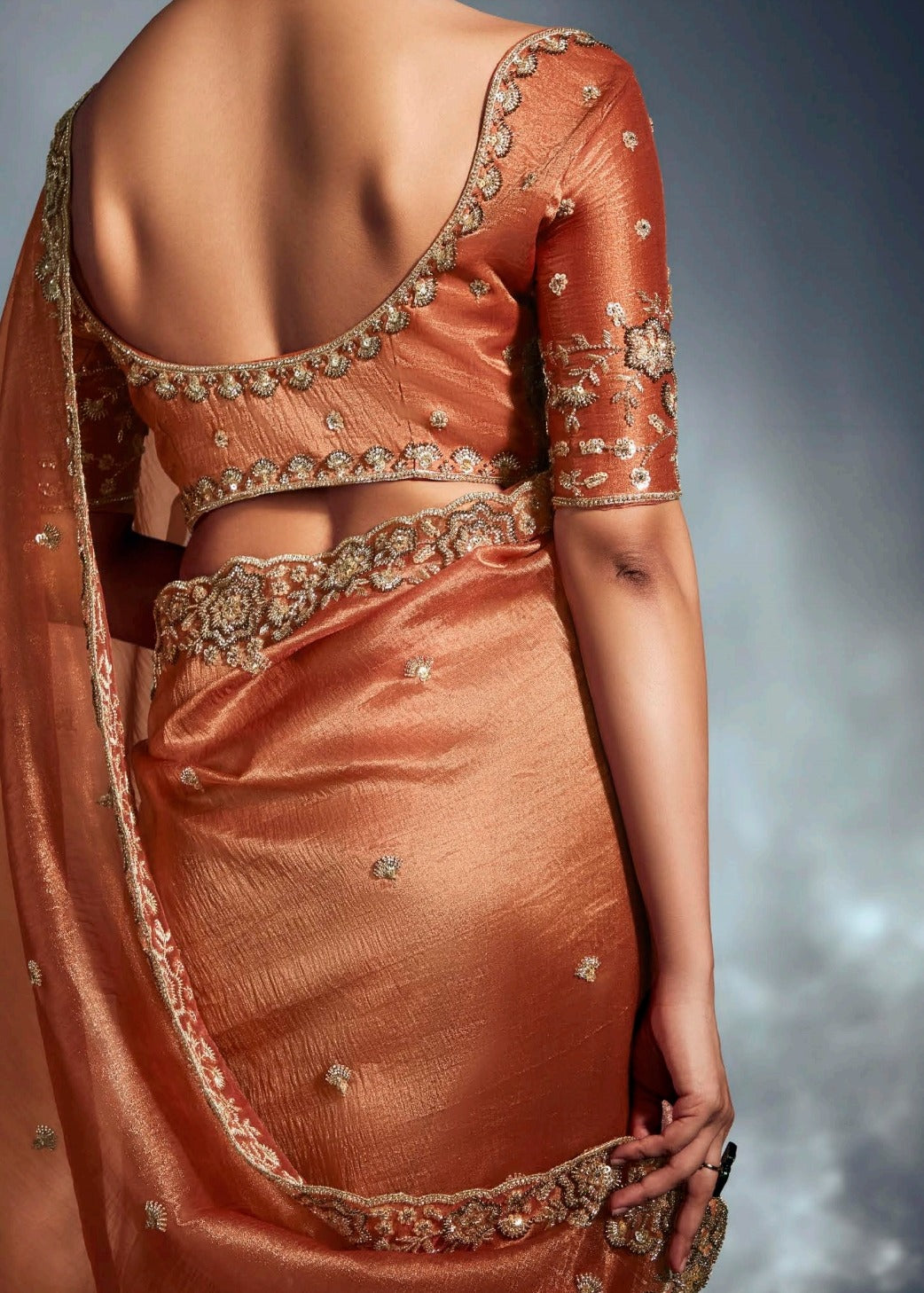 Rust orange tissue silk saree with handcrafted embroidery for traditional indian wedding functions.