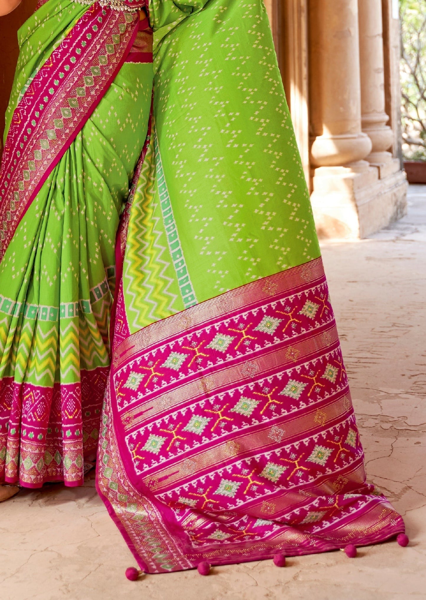 Green patola silk saree online design featuring contrast pink pallu and zari border.