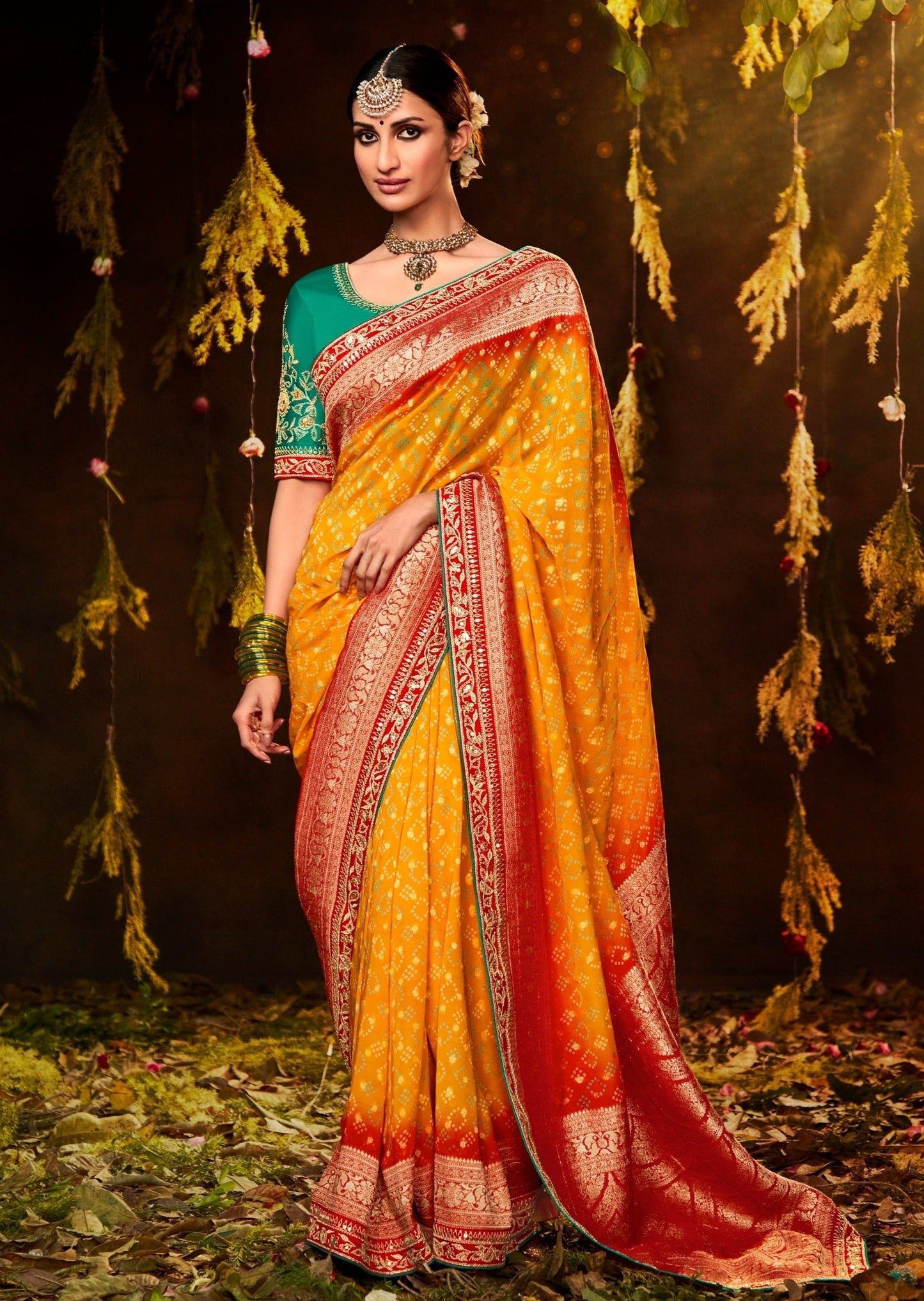 Woman in yellow bandhani bridal saree with contrast green embroidered blouse.