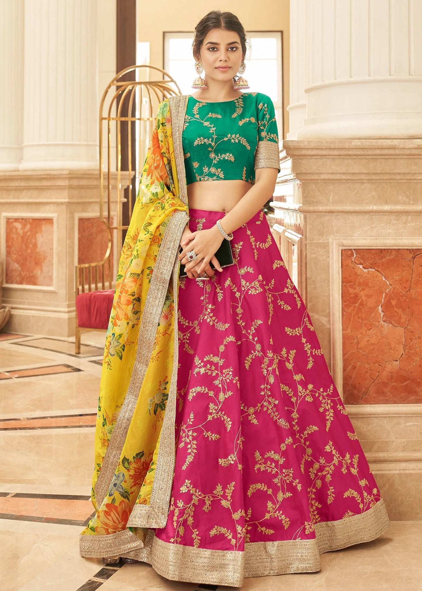 Pink silk lehenga with gota patti and mirror work border, 4.5 meter flair with can-can, paired with parrot green raw silk choli with sweetheart neckline and dori tie back, yellow organza dupatta with digital marigold floral print and pink gota lace, handmade tassels, haldi mehendi bridal lehenga set.
