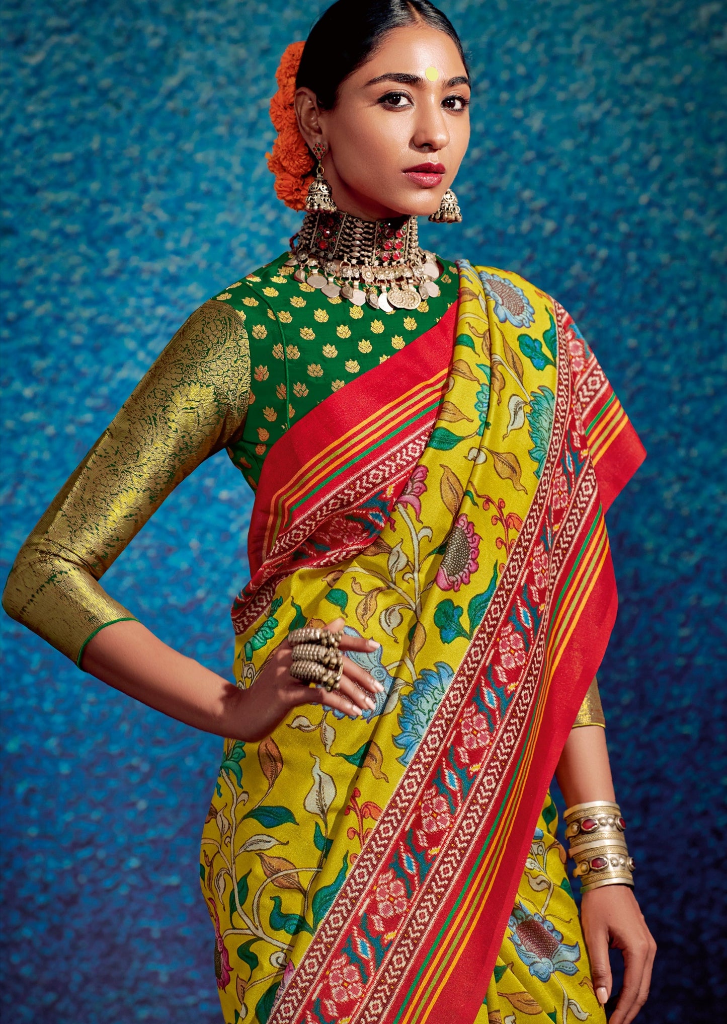 Woman standing in Kalamkari Patola Fusion Yellow Saree and green blouse with hand on waist 