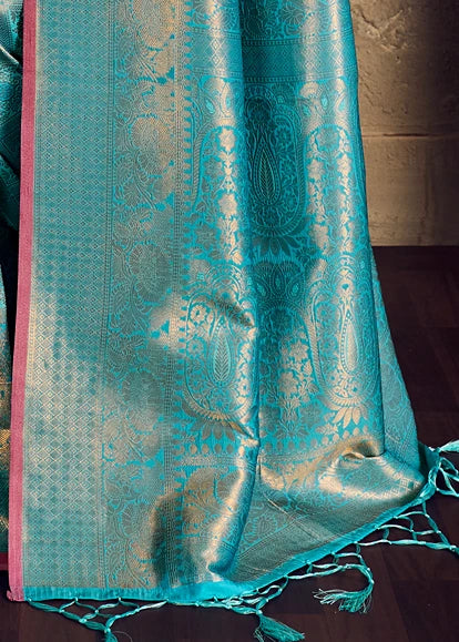 Close-up pallu shot of the intricate gold zari embroidery on a turquoise Banarasi silk saree showcasing its geometric and floral designs.