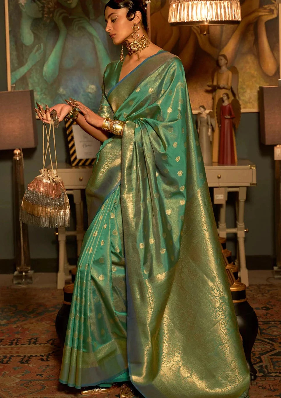 woman standing in front of console table wearing green  colour banarasi silk saree with golden border