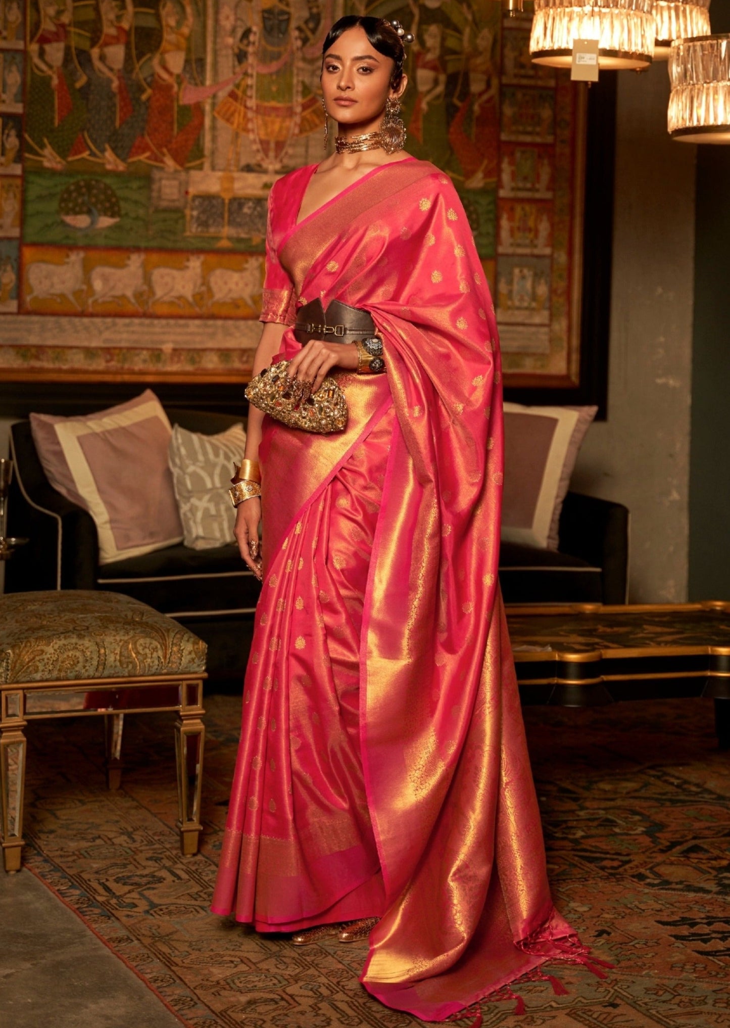 woman standing in front of black sofa wearing banarasi Silk red Handloom Bridal Saree holding golden purse in left hand