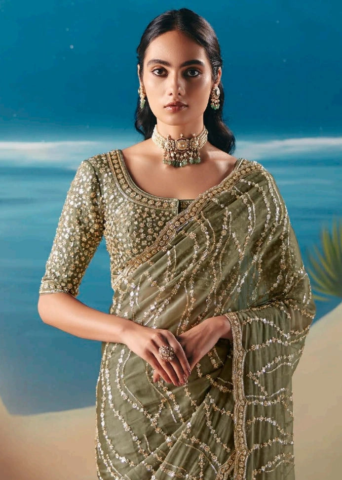 Closeup of olive green organza tissue silk saree with intricate beadwork and sequin hand embroidery on sheer fabric.