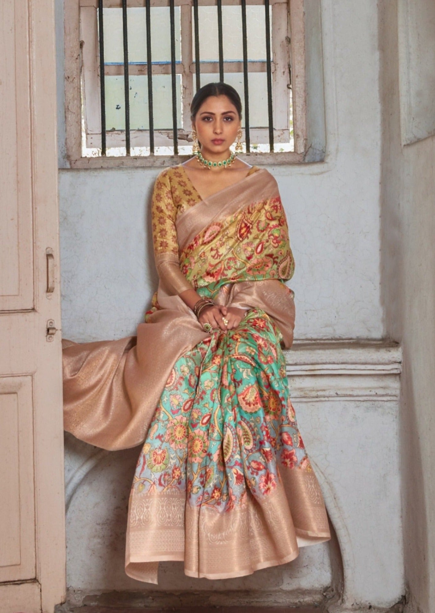 Woman sitting on bench wearing beige kalamkari saree with banarasi border