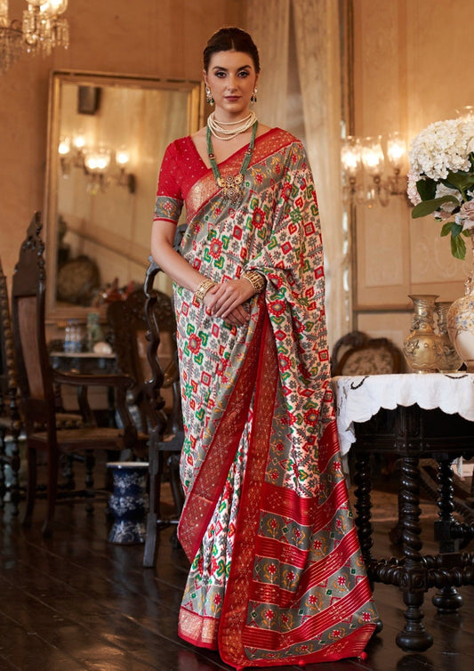 Woman in white mirror work patola saree & red blouse.