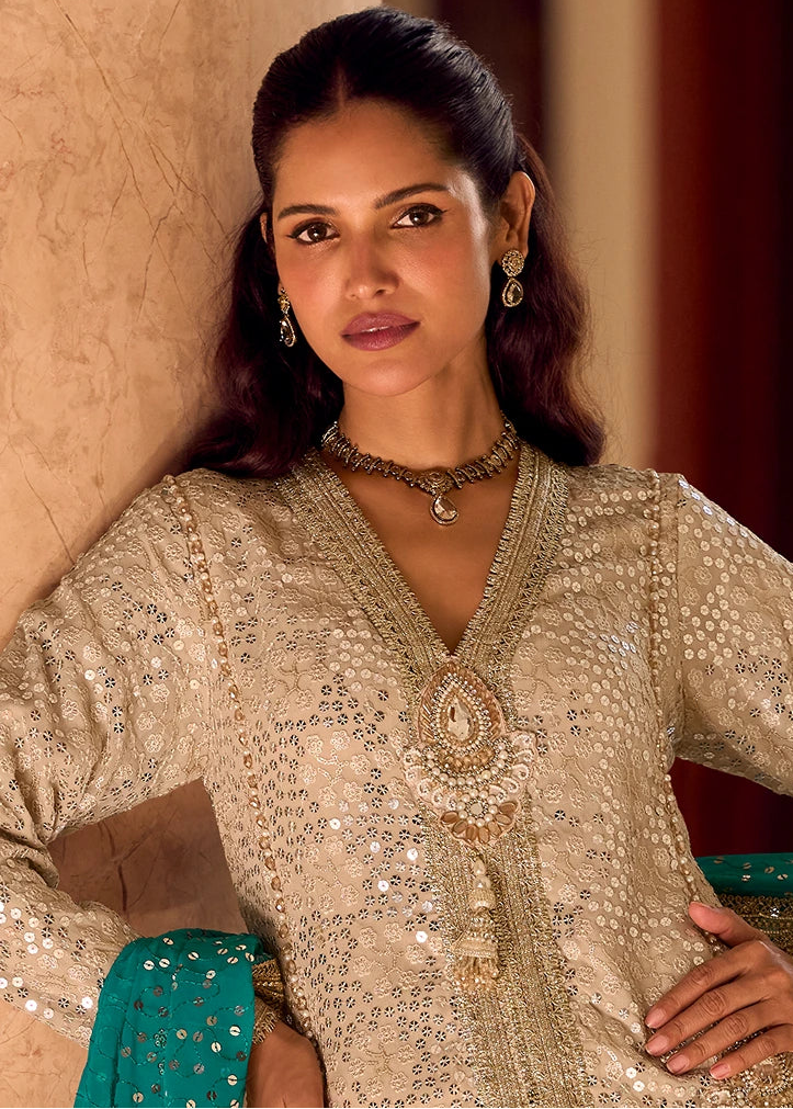 A woman wearing a heavily embellished beige and gold traditional indian ethnic co ord set outfit with intricate mirror and sequins work, paired with a turquoise blue dupatta, for wedding function.