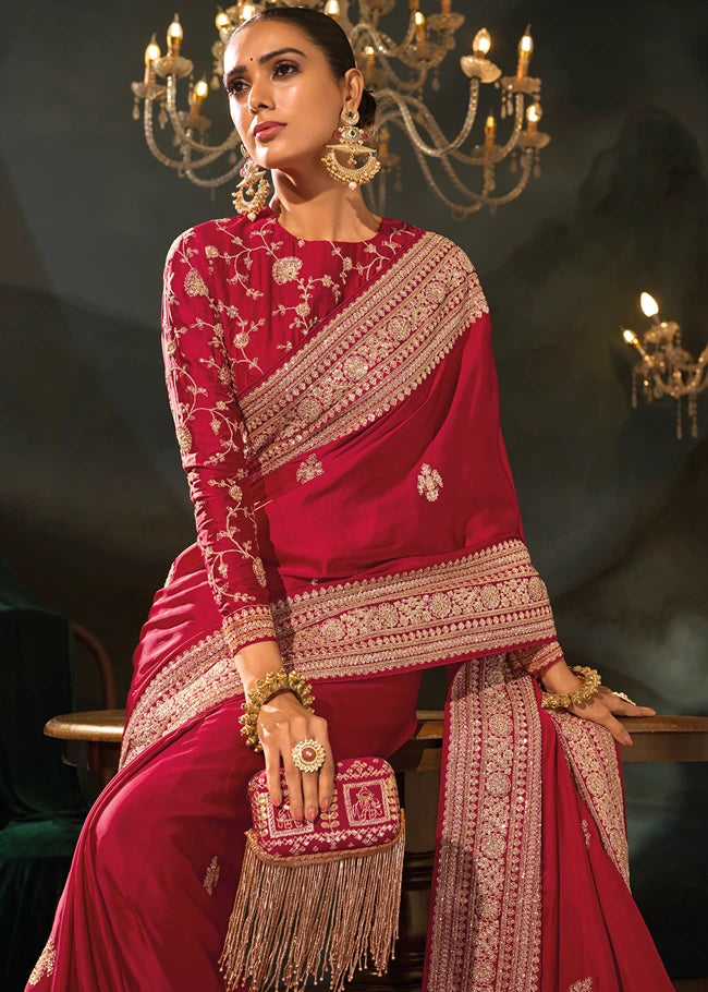 Detailed macro view of the thick golden zari embroidered border on the vibrant red silk fabric.