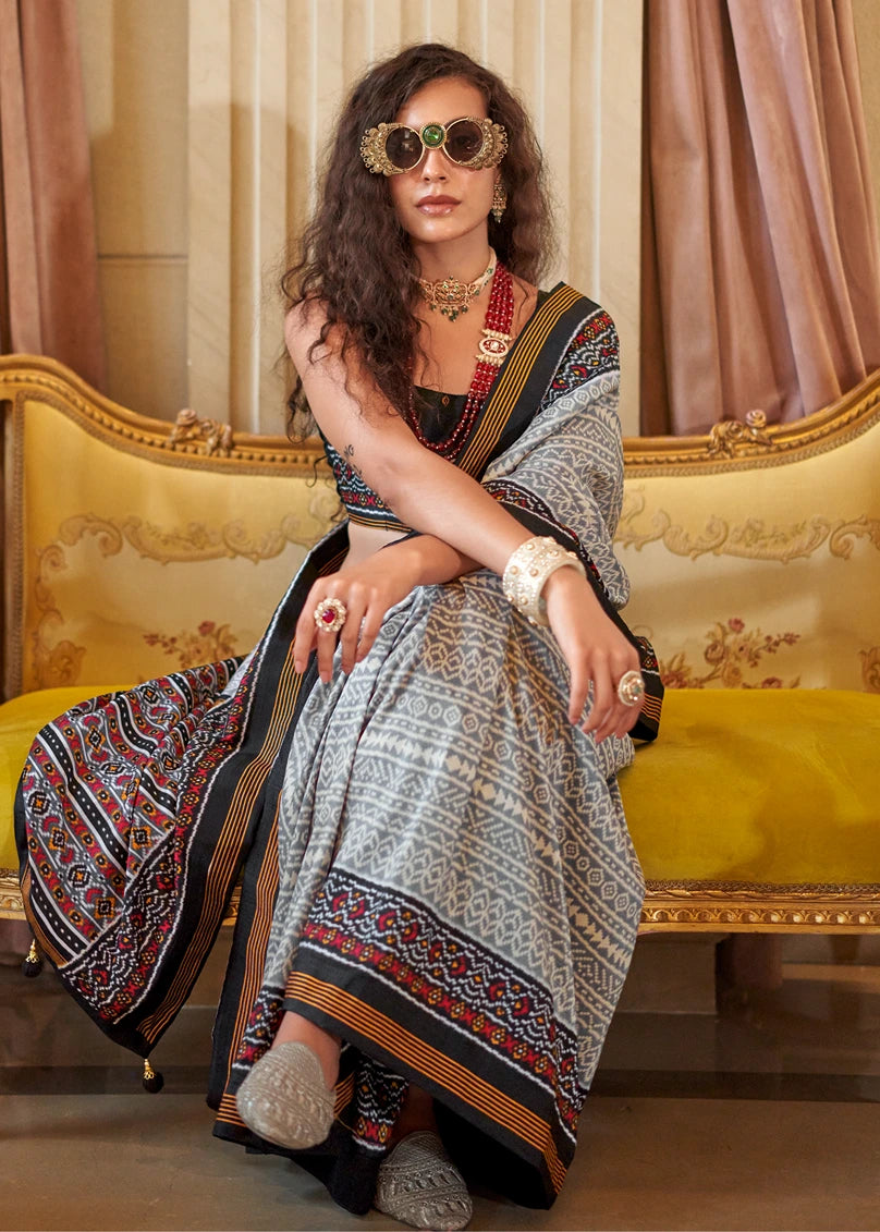 Elegant patola silk saree in grey with rich black pallu and traditional detailing available at best price.