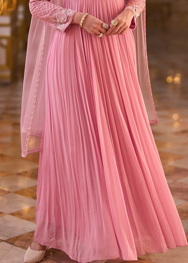 A pink pleated anarkali gown dress with hand embroidered long sleeves and a matching sheer dupatta, shown on a woman.