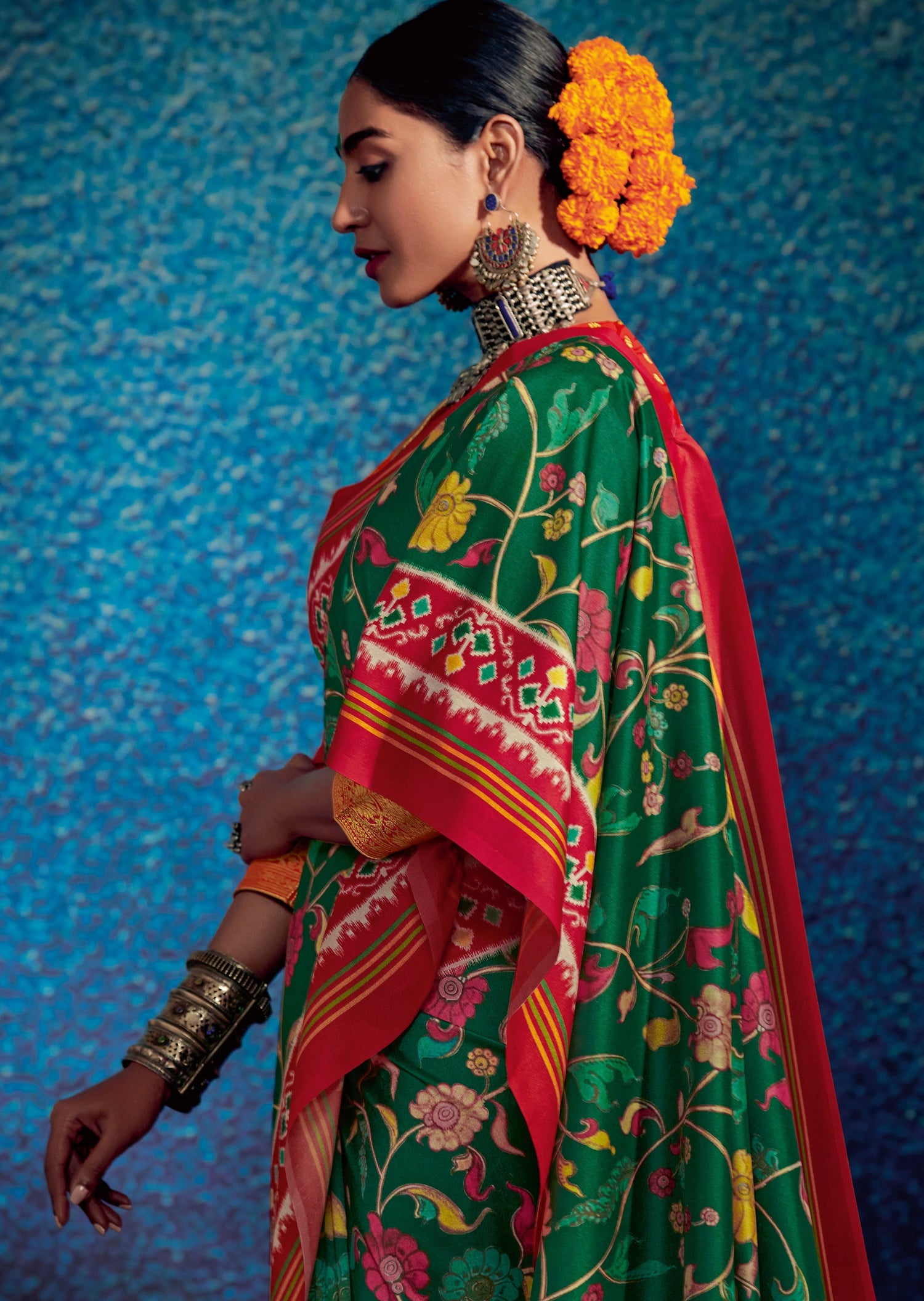 Woman wearing marigold garland in hair wearing green Kalamkari Patola Fusion saree