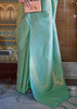 Pastel green kanjivaram silk saree pallu design with intricate gold zari embroidery and border patterns, worn by a woman in USA.