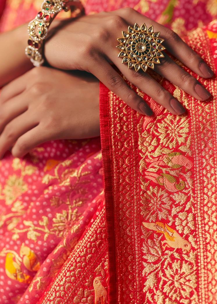 Close-up of pastel pink khaddi banarasi georgette saree featuring red border and all over meenakari floral patterns with zari weaving.