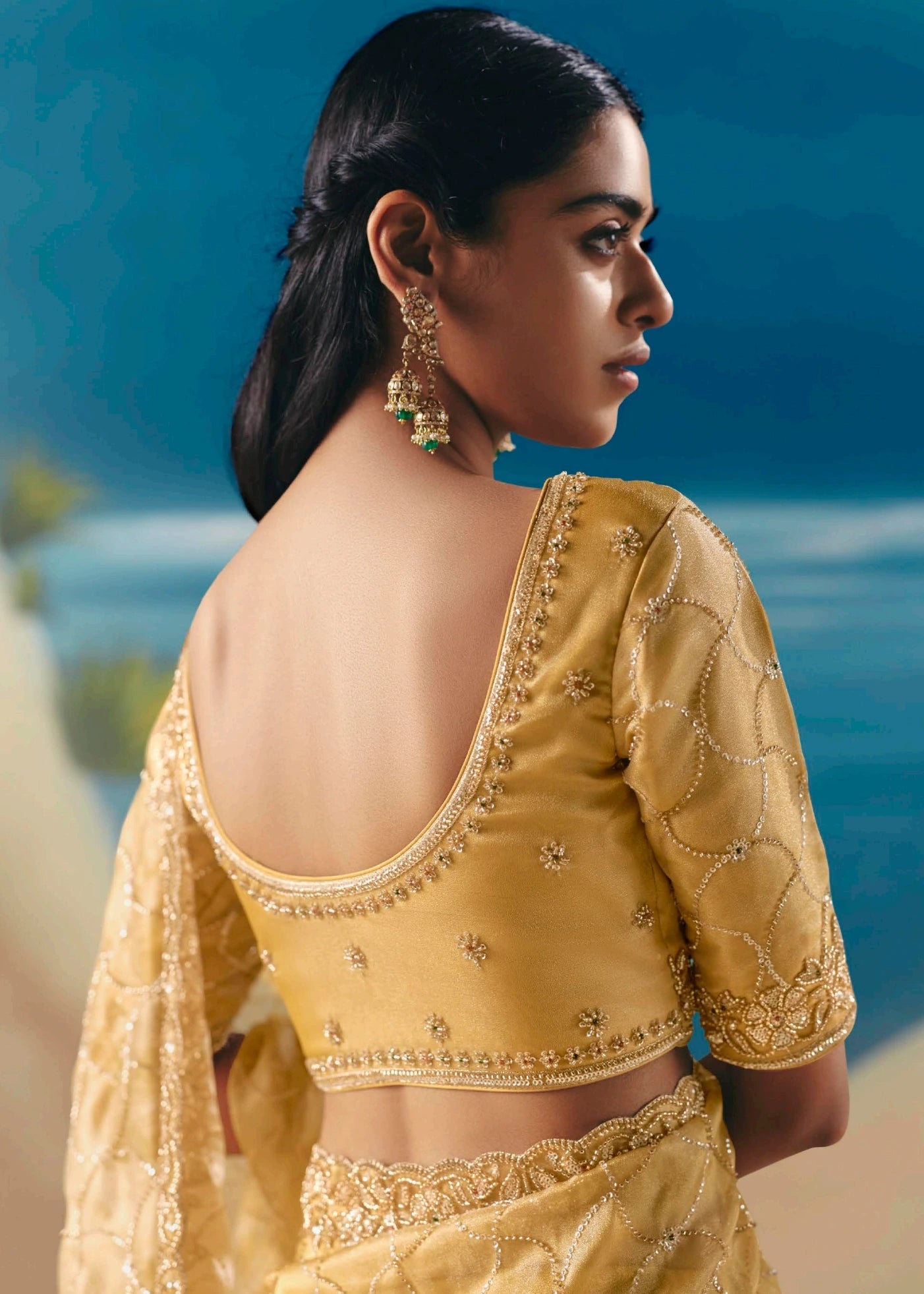 Lightweight pastel yellow hand embroidered organza tissue silk wedding saree with deep cut blouse back featuring sequins and beadwork embroidery.