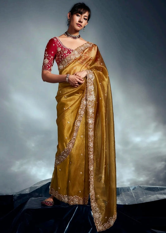 Luxury golden mustard yellow tissue silk embroidered saree with contrast red blouse for wedding and reception look.
