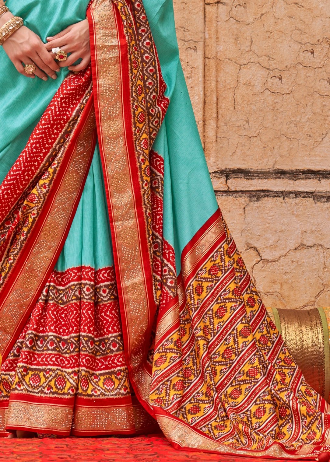 Shop designer ocean green patola silk saree with contrast red blouse at best price.