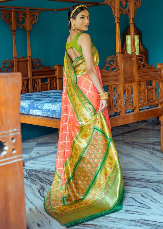 Traditional orange banarasi patola silk handloom saree with contrast green blouse featuring ikat weave and zari weaving.