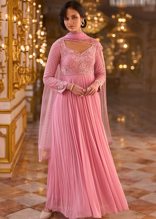 Woman modeling a pastel pink georgette anarkali gown with an embroidered bodice, long sleeves, and net dupatta.
