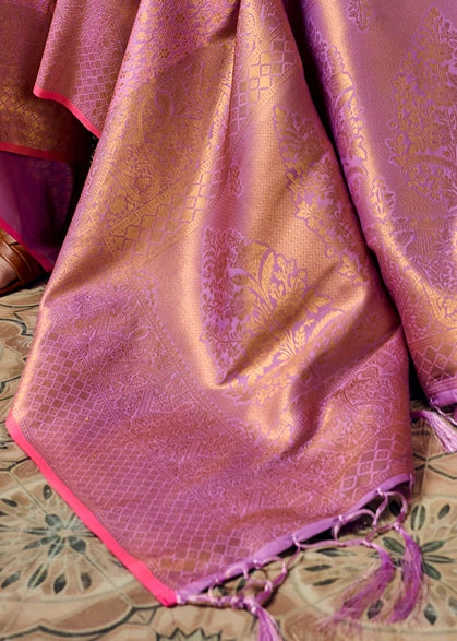 Close-up of a draped pastel pink and gold bridal kanchipuram saree pallu, featuring intricate floral motifs, a geometric lattice border and tassels.