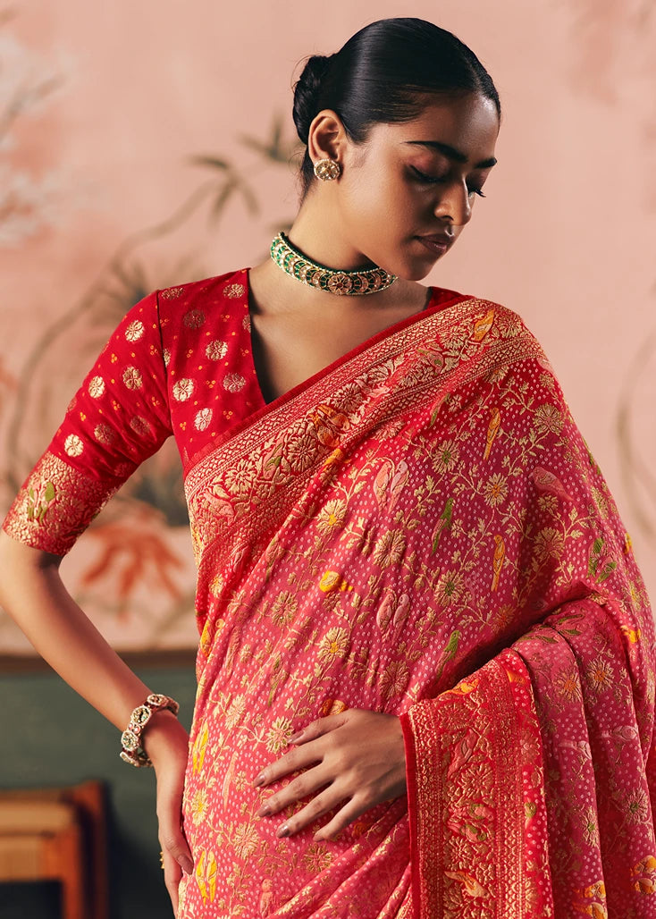 Woman wearing a red and pink bandhani saree with intricate patterns, paired with contrast red blouse featuring butta and sleeve border.