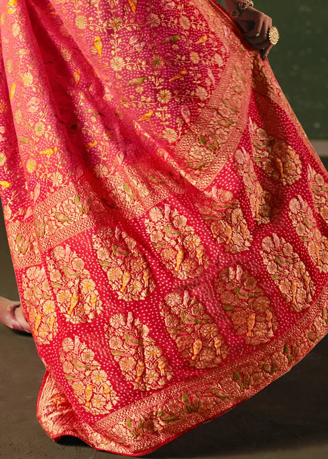 Close-up of pastel pink and red bridal bandhani saree in banarasi khaddi georgette fabric with gold floral patterns and shikargah motifs.
