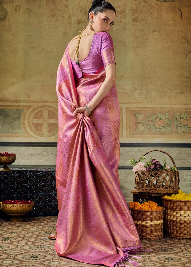 A woman wearing a powder pink kanchipuram silk saree with gold zari geometric motifs and a matching pink blouse.