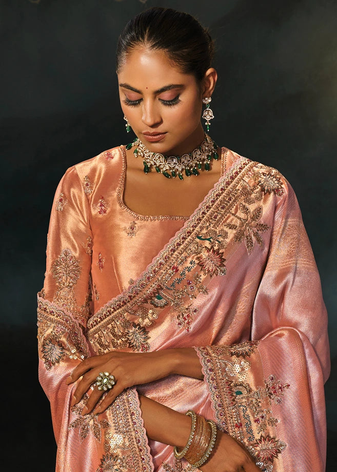 Macro view of gold zari embroidery and meticulous hand-stitched beadwork on premium pastel pink Kanjivaram silk saree fabric.