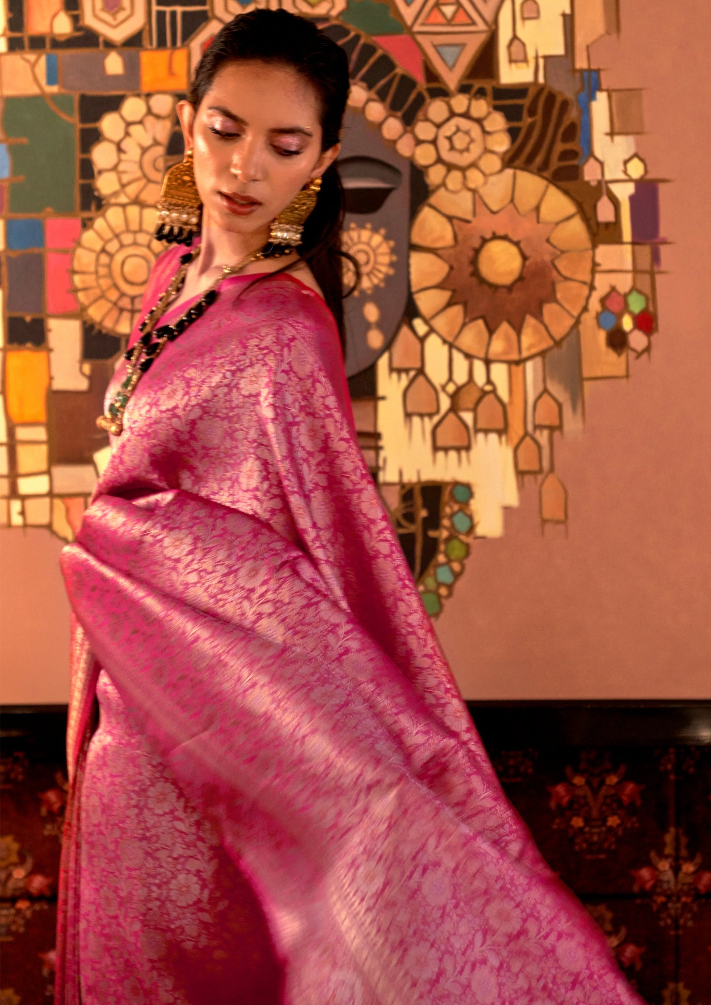 woman flaunting her pink banarasi silk saree and gold jewelry