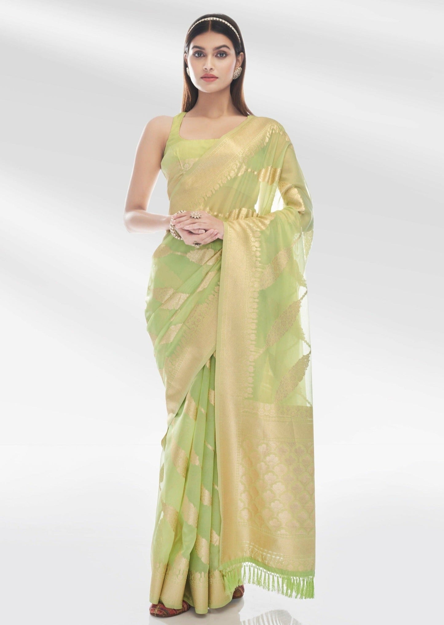 Woman standing in pure banarasi organza lime green saree blouse.