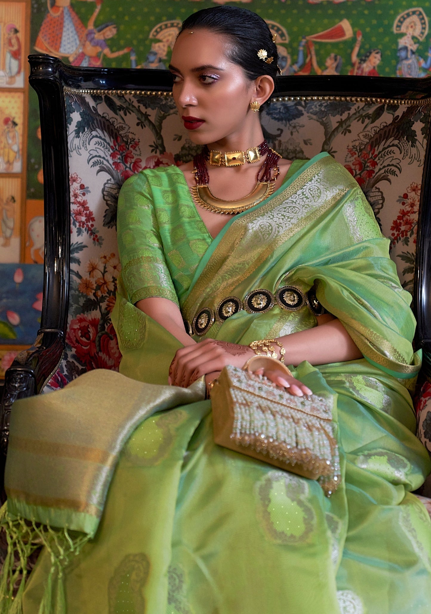 woman in Pure Handloom Zari Banarasi Organza Saree Light Green colour sitting on chair.