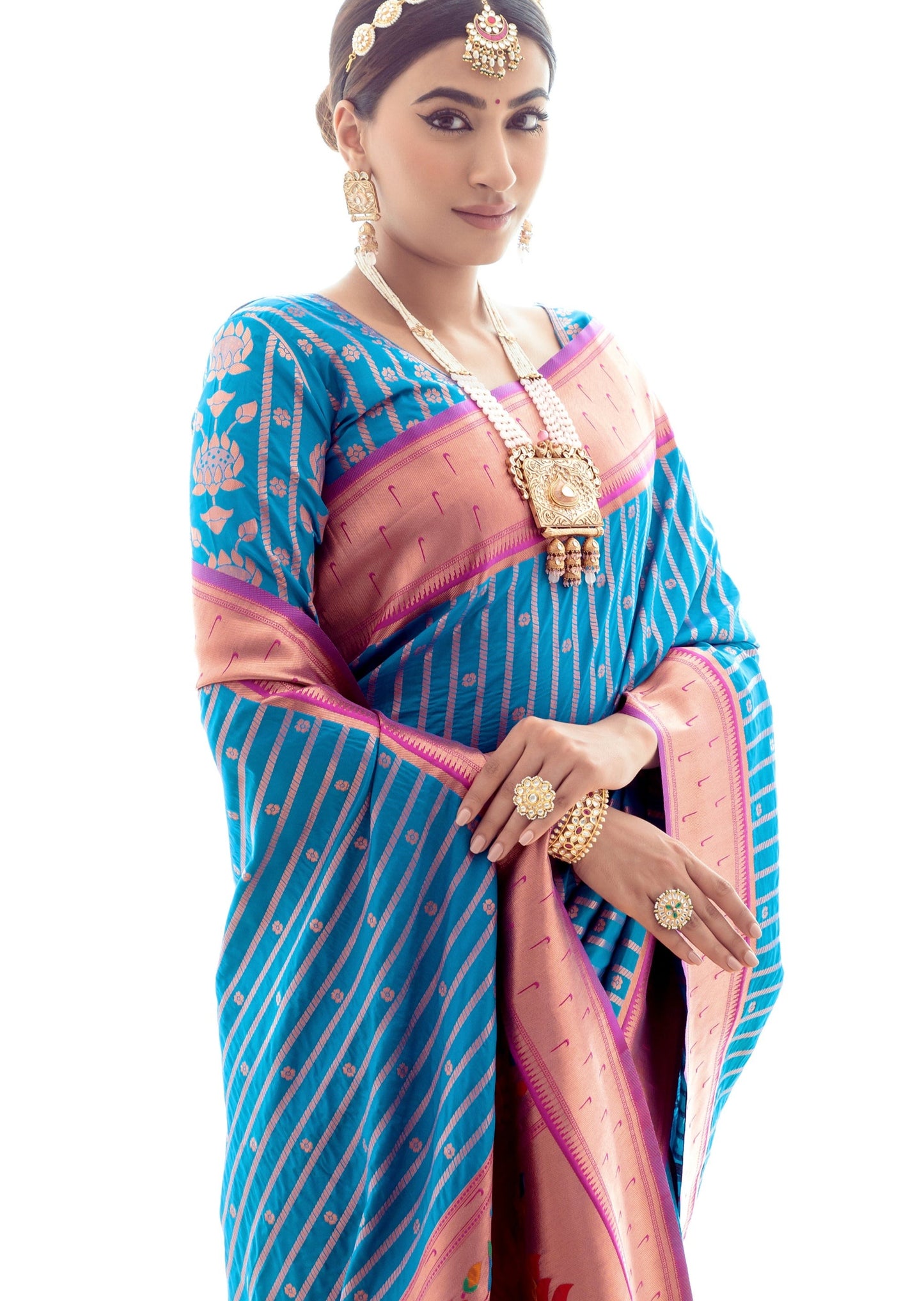 Woman wearing blue silk saree and Indian jewellery like pearl rani haar, matha patti