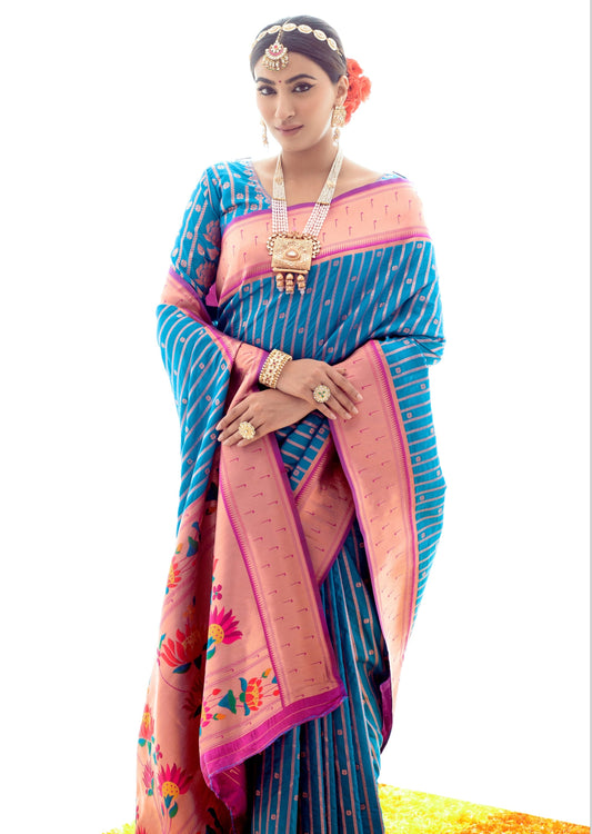 Woman standing in front of white wall wearing pure paithani silk blue handloom saree with zari border