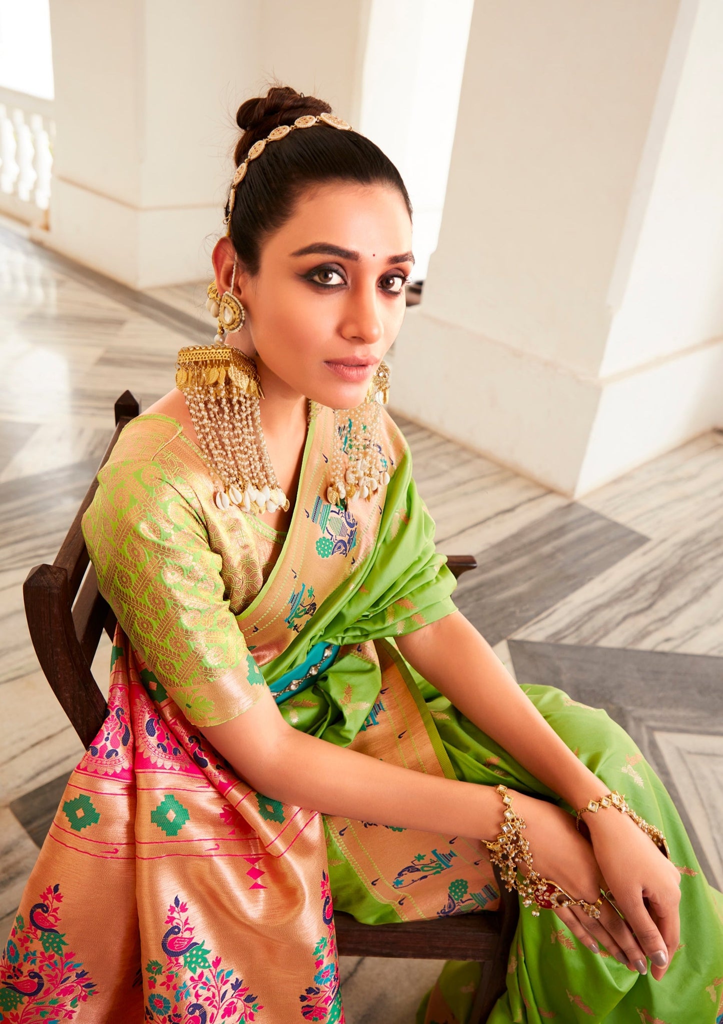 woman sitting in chair wearing lawn green paithani silk handloom saree