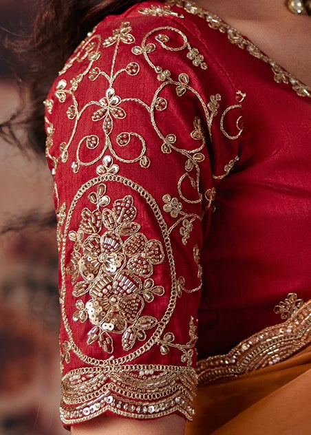 Close-up of a red embroidered blouse sleeve with intricate gold sequin florals, beadwork and thread work, worn by a woman.