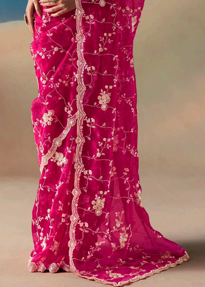 Pinkish red hand embroidered organza tissue silk saree with sequin and beadwork on sheer pallu and graceful pleats for bridal drape.