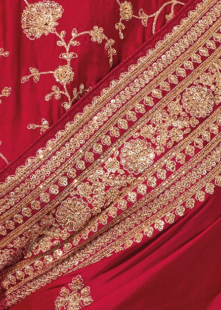Close-up shot of heavily detailed golden thread embroidery and traditional motifs on red silk saree.