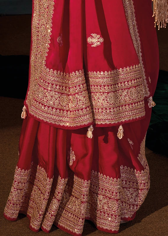 Close-up view of the perfectly tucked pleats of a red silk saree, highlighting the consistent embroidery pattern.