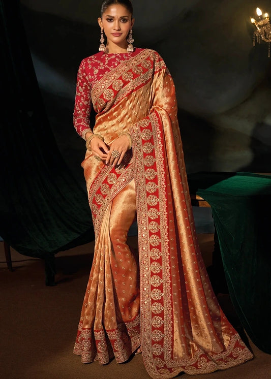 Full-length studio shot of a luxurious rust orange Kanjivaram pure silk saree featuring elaborate gold zari embroidery and a contrasting crimson red blouse.