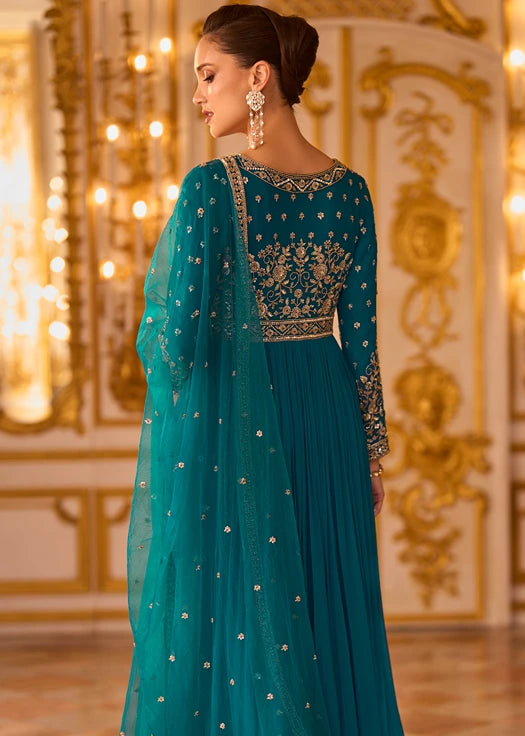 A woman wearing a teal blue anarkali gown with gold embroidery, shown from the back.