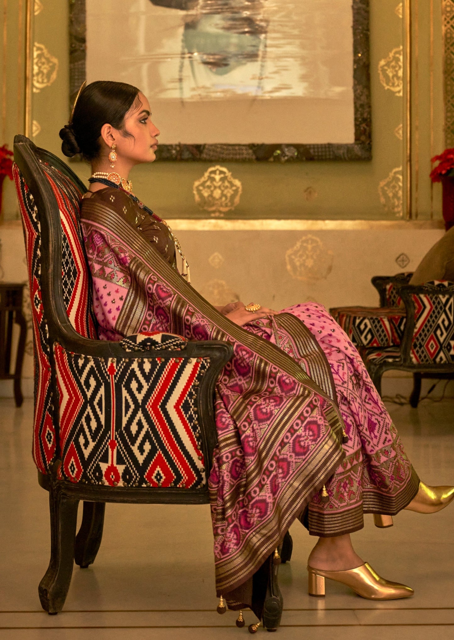 Woman in pink color Patola Saree sitting in chair