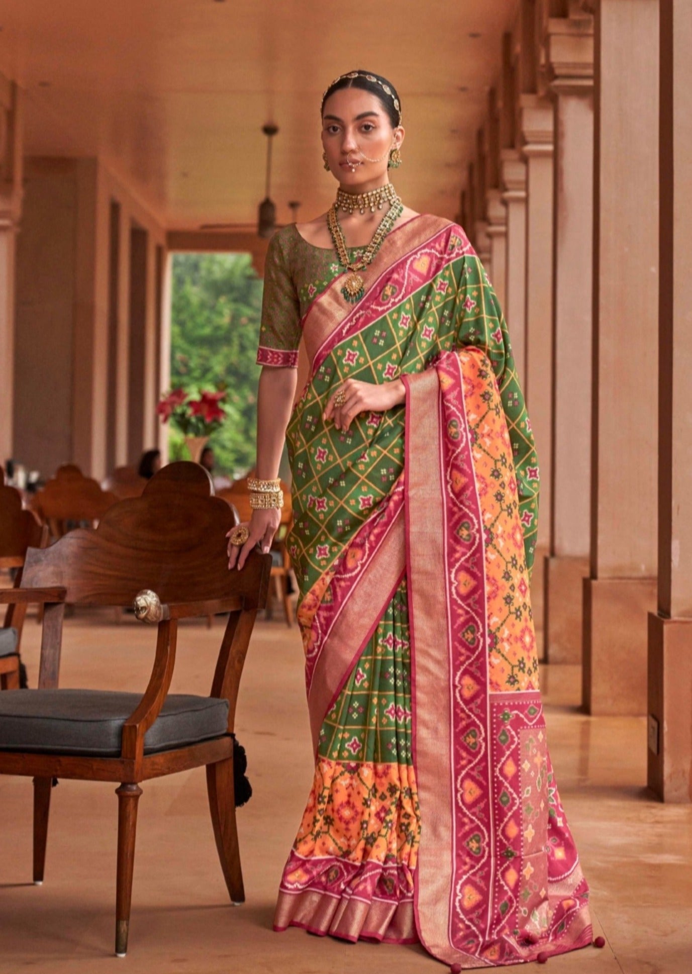 Woman standing against chair wearing green-ikat-patola-saree