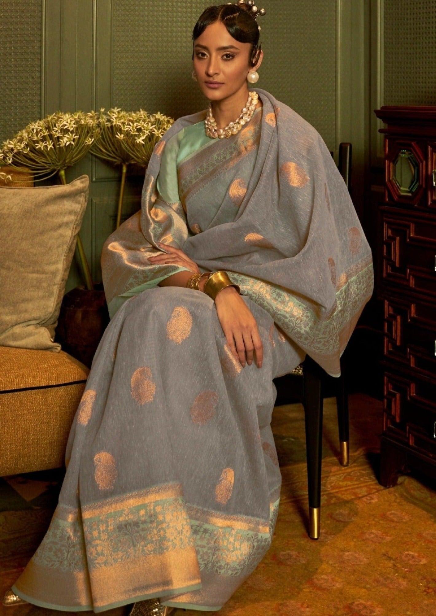 Pure linen handloom saree in grey color on a woman sitting on a chair.